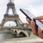 Woman in Paris using her cell phone in front of Eiffel Tower